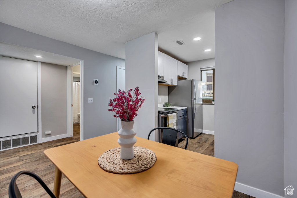 Dining space with wood finished floors, baseboards, and recessed lighting