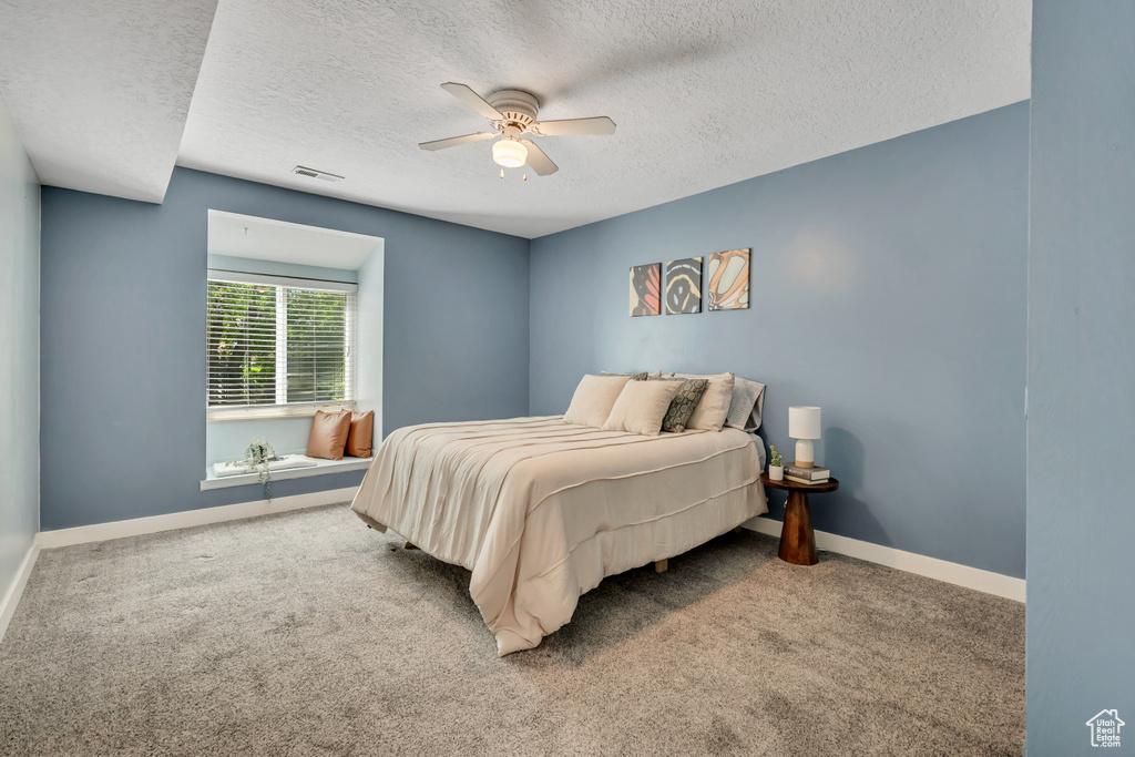 Bedroom featuring a textured ceiling, carpet flooring, ceiling fan, and baseboards