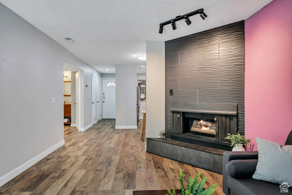 Living room with baseboards, wood finished floors, track lighting, and a multi sided fireplace