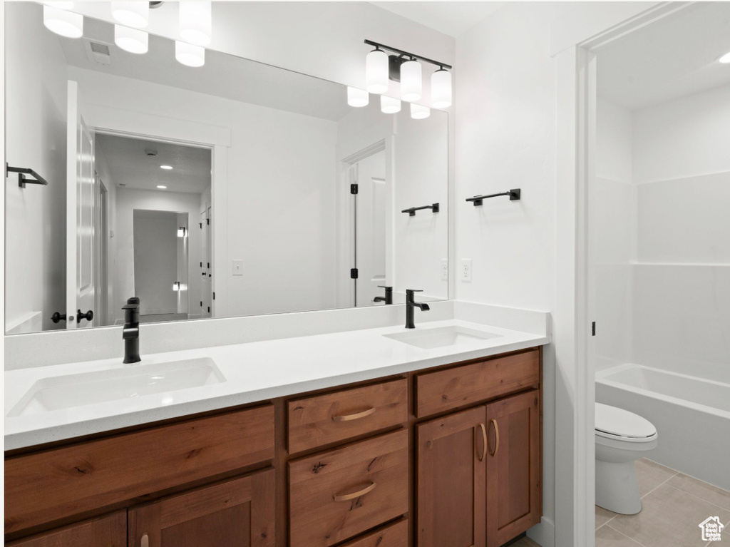 Full bath featuring toilet, tile patterned flooring, double vanity, and a sink