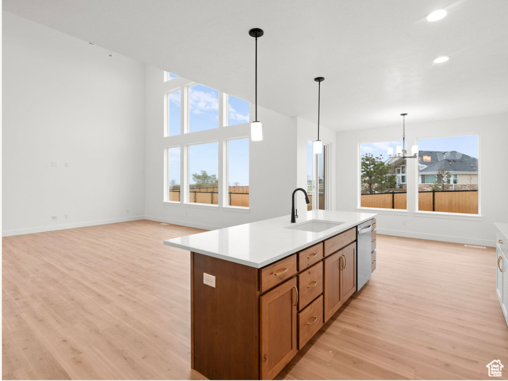 Kitchen with recessed lighting, light wood-style flooring, brown cabinets, dishwasher, and a sink