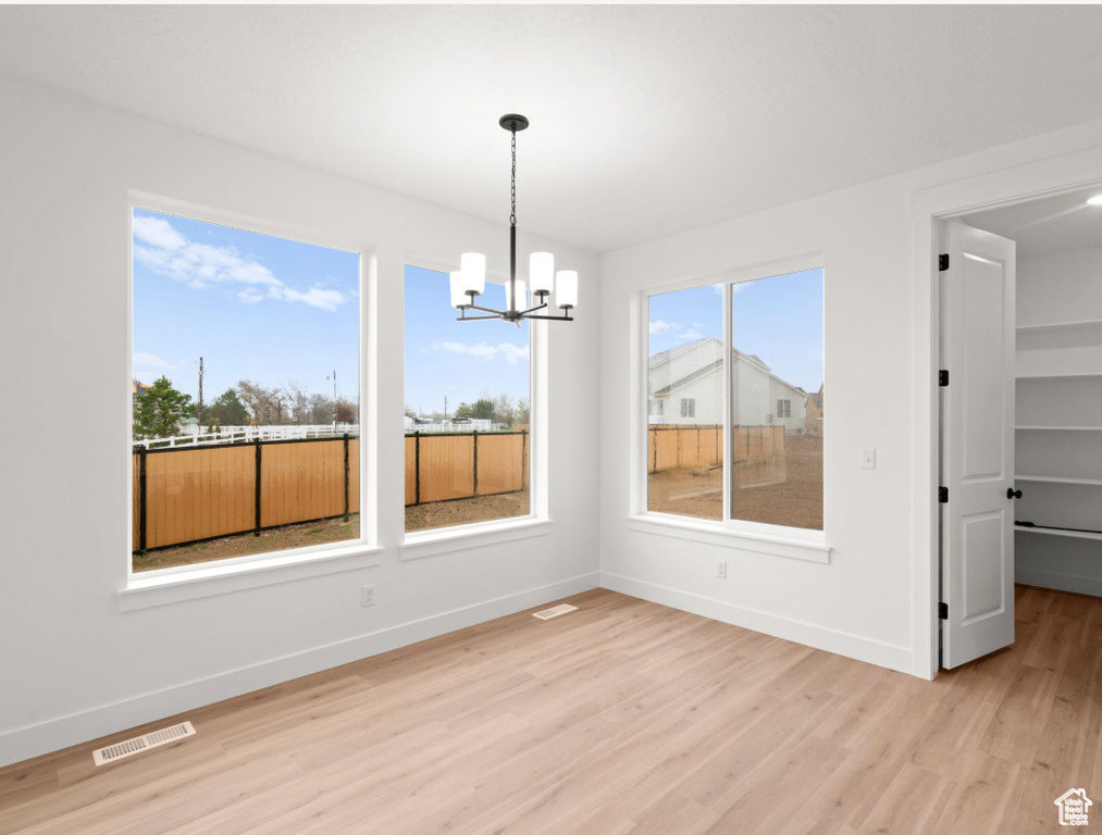 Unfurnished dining area featuring baseboards, visible vents, an inviting chandelier, and light wood-style floors