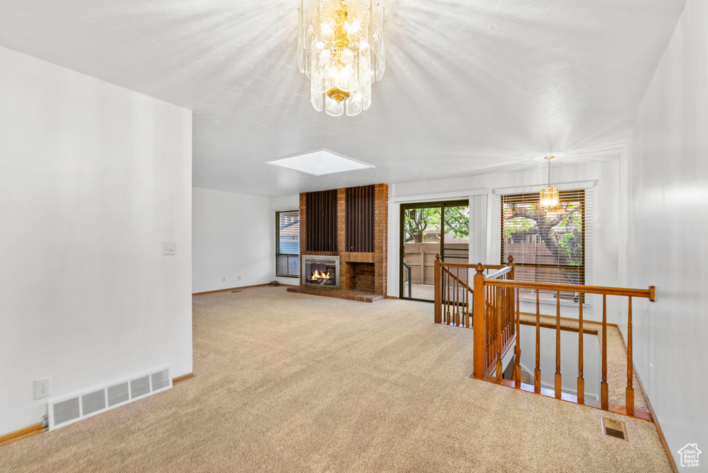 Interior space with a fireplace, visible vents, carpet, baseboards, and a skylight