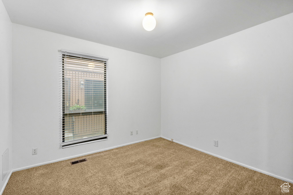 Unfurnished room featuring carpet flooring, visible vents, and baseboards