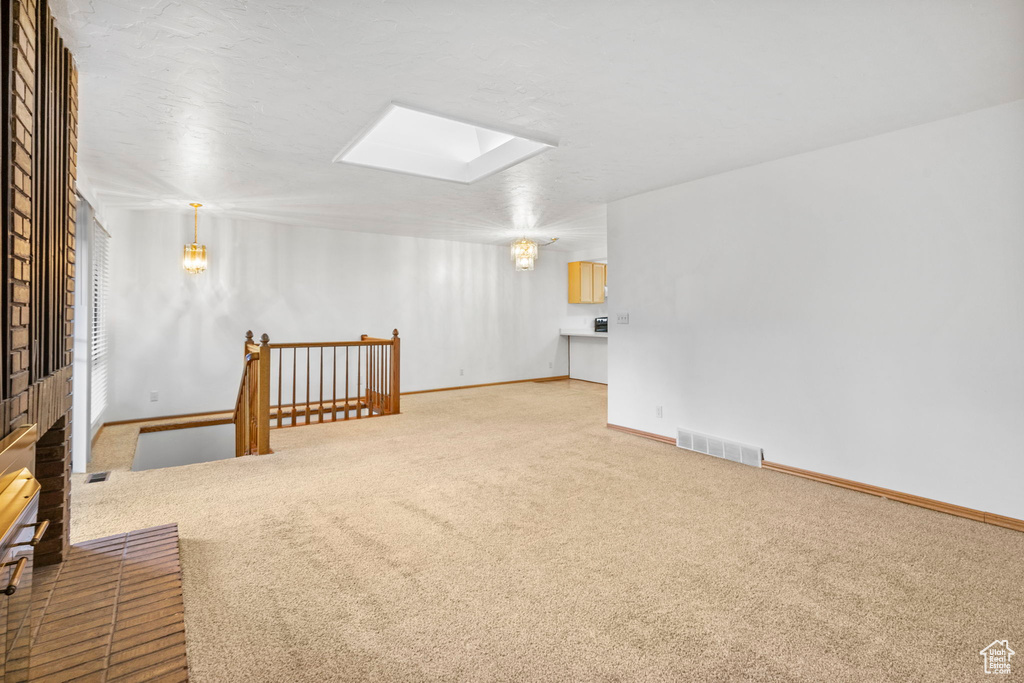 Interior space with visible vents, baseboards, carpet flooring, and a skylight
