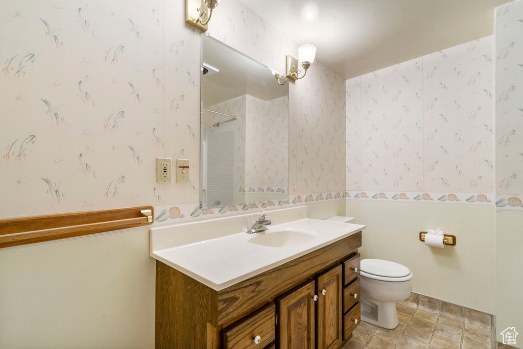 Full bathroom featuring wallpapered walls, walk in shower, toilet, and vanity