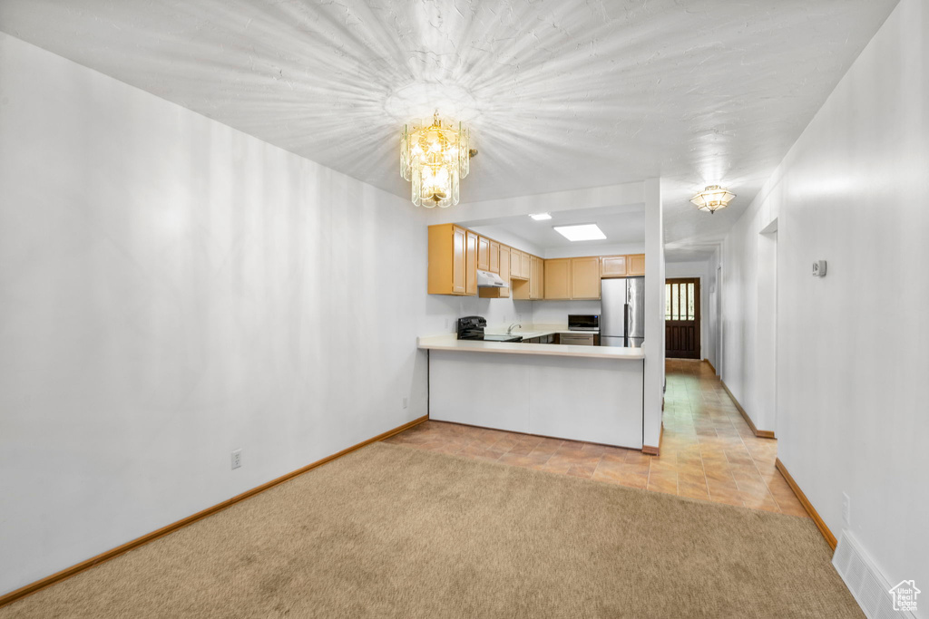 Kitchen with visible vents, stainless steel appliances, light countertops, light carpet, and a notable chandelier