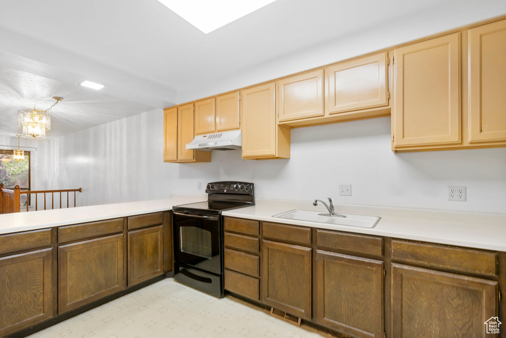 Kitchen featuring black electric range oven, a sink, visible vents, light countertops, and under cabinet range hood