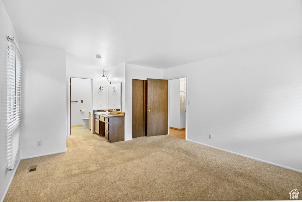 Unfurnished bedroom featuring baseboards, visible vents, light carpet, and connected bathroom