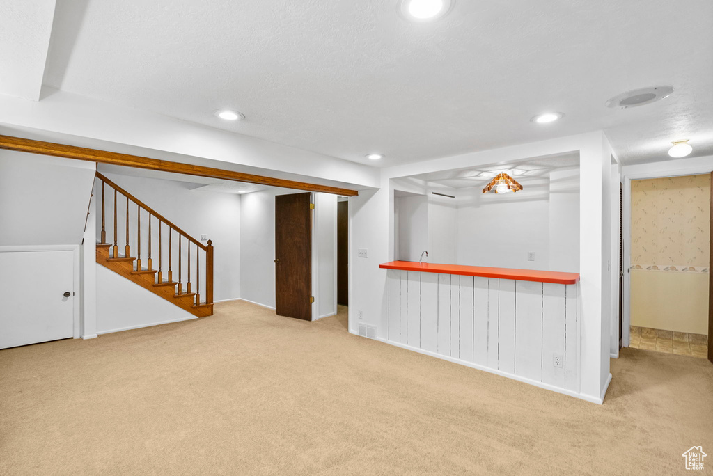 Finished below grade area featuring recessed lighting, carpet, baseboards, stairway, and indoor bar