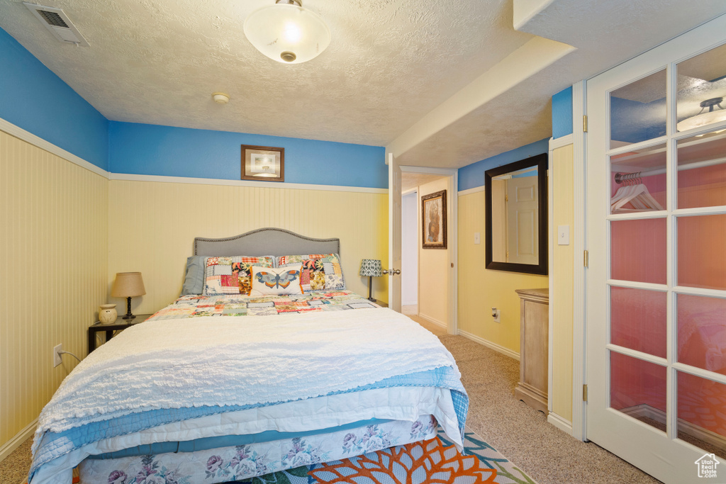 Bedroom with carpet flooring, a textured ceiling, visible vents, and baseboards
