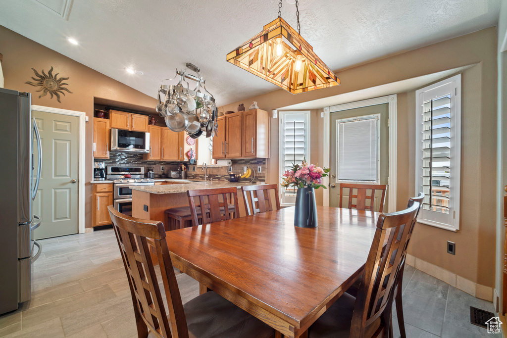 Dining room with baseboards, visible vents, an inviting chandelier, and vaulted ceiling