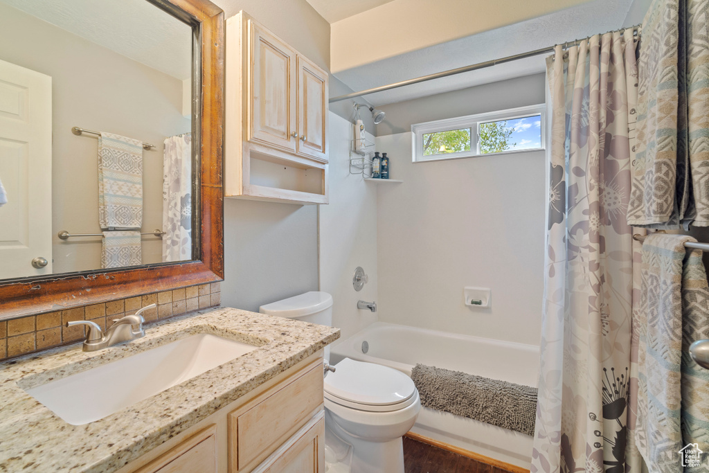 Full bathroom featuring shower / bath combo, vanity, toilet, and backsplash