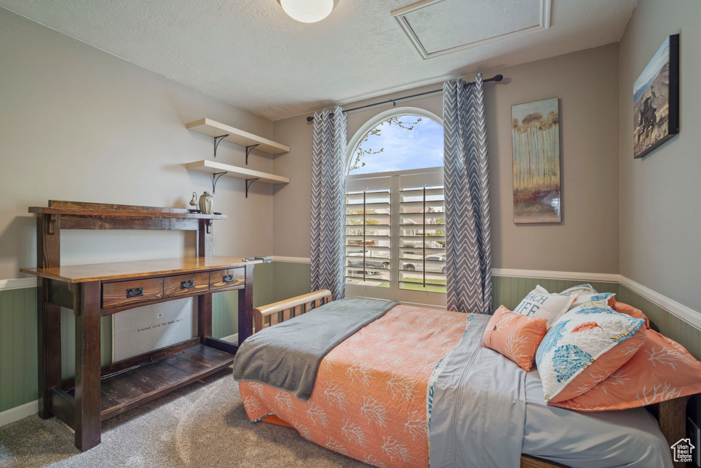 Carpeted bedroom with attic access and wainscoting