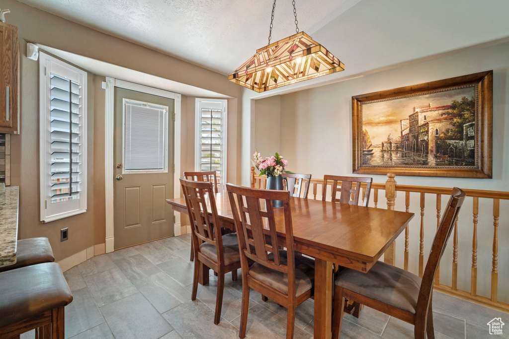 Dining room featuring a textured ceiling, plenty of natural light, a notable chandelier, and baseboards