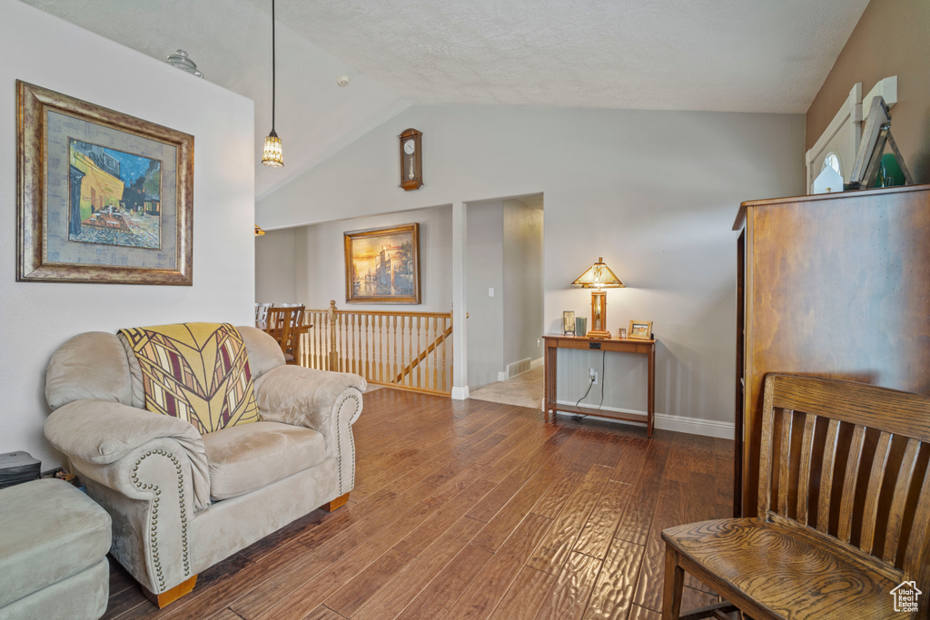 Living area featuring wood finished floors, visible vents, vaulted ceiling, and baseboards