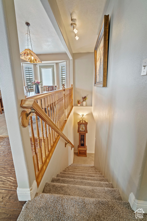 Stairs featuring a textured ceiling and baseboards