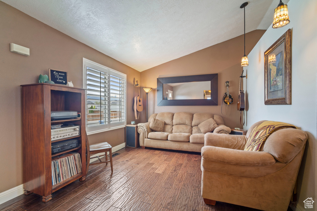 Living room featuring lofted ceiling, wood finished floors, and baseboards