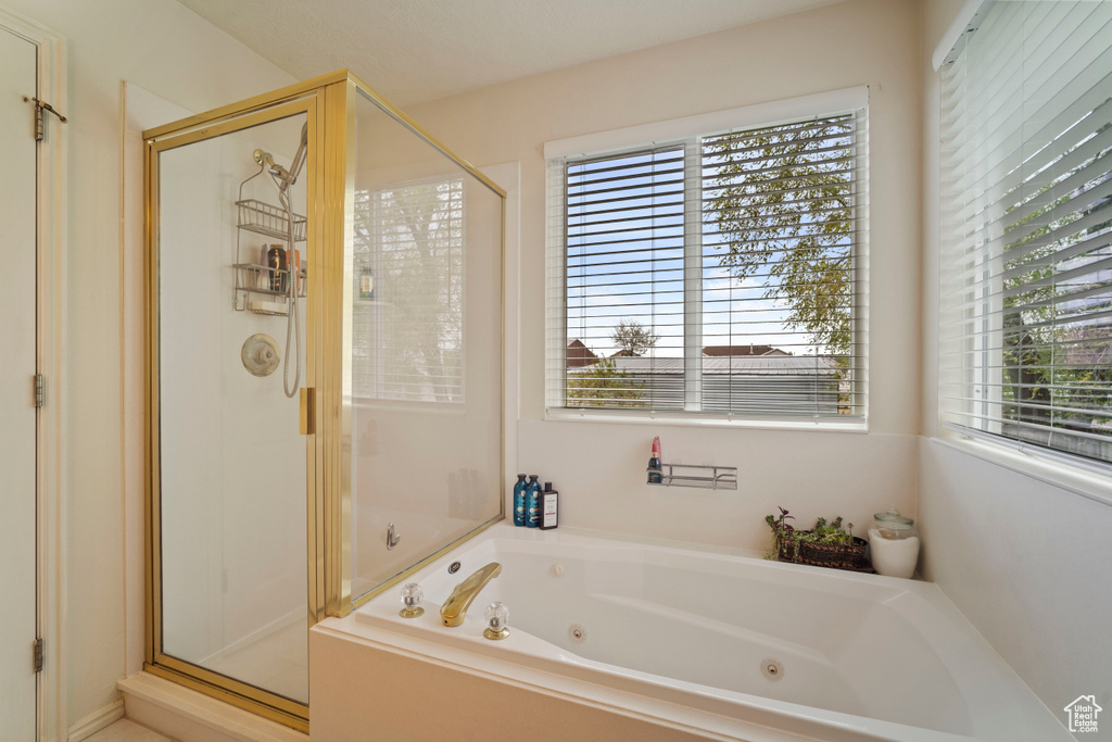 Bathroom featuring a tub with jets and a stall shower