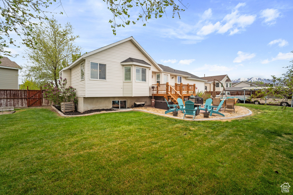 Back of property featuring a lawn, a deck, a patio area, and fence