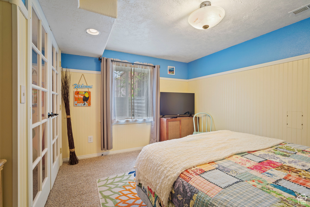 Bedroom with visible vents, carpet, baseboards, a textured ceiling, and french doors