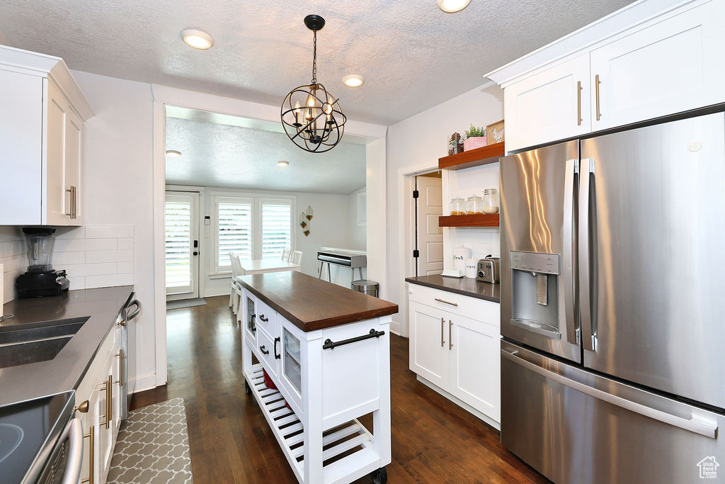 Kitchen featuring tasteful backsplash, open shelves, appliances with stainless steel finishes, and a textured ceiling