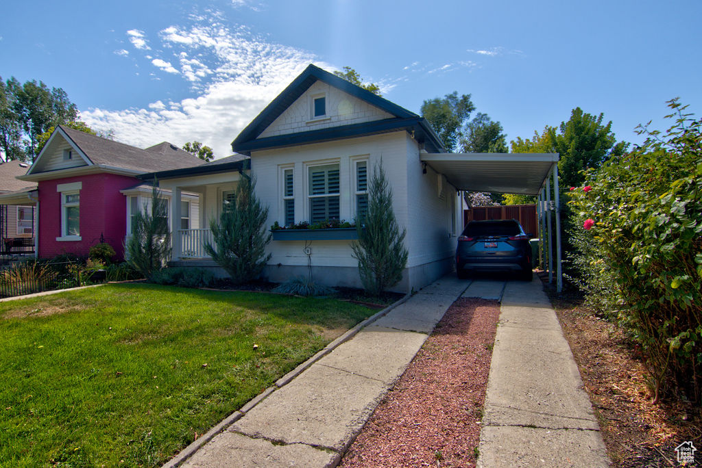 View of front of property featuring a carport, driveway, a front lawn, fence, and covered porch