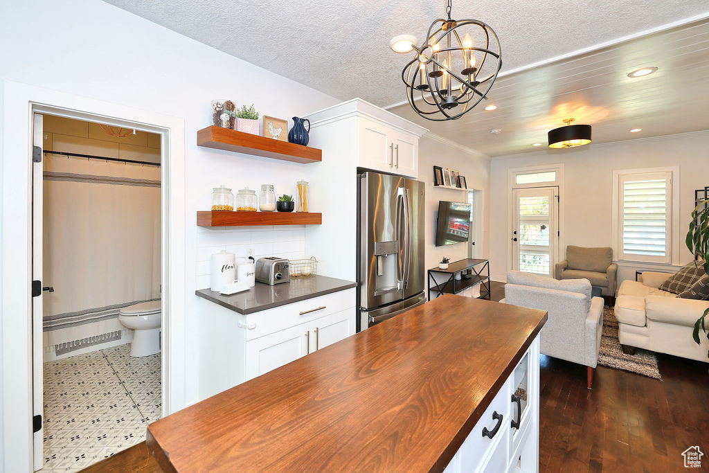 Kitchen with an inviting chandelier, recessed lighting, open shelves, wooden counters, and stainless steel refrigerator with ice dispenser