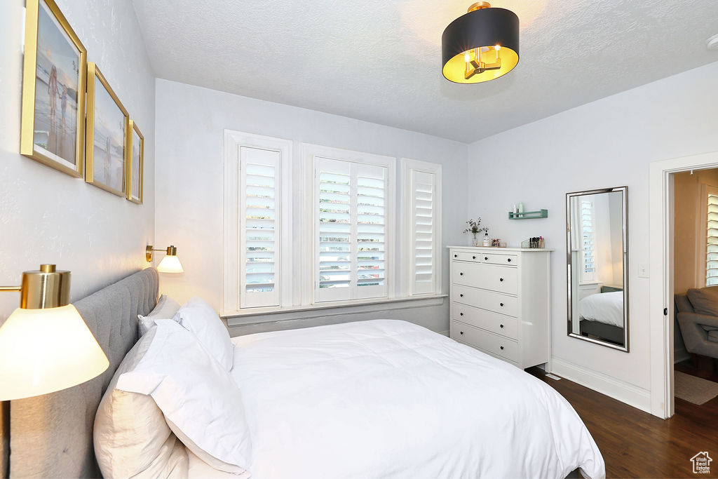Bedroom with baseboards, a textured ceiling, and dark wood-style floors