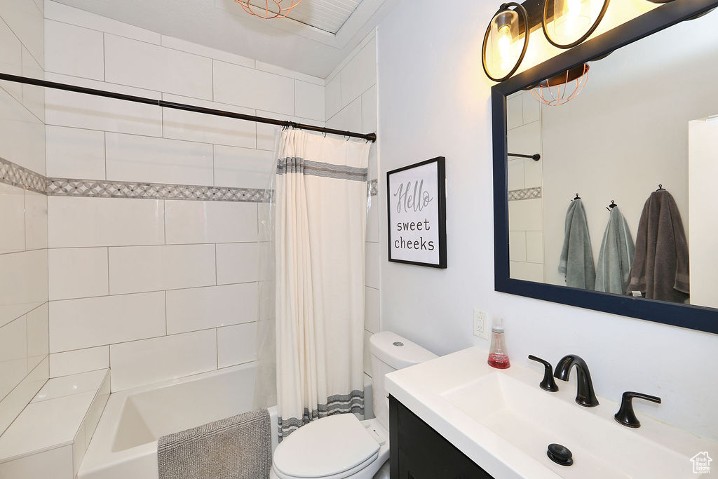 Full bathroom with toilet, shower / tub combo with curtain, and vanity