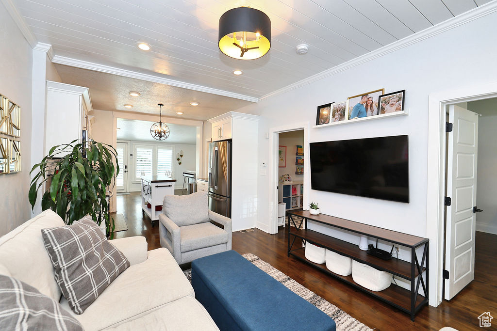Living room featuring dark wood-type flooring, baseboards, ornamental molding, and recessed lighting