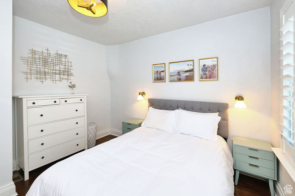 Bedroom with dark wood-style floors, baseboards, and a textured ceiling