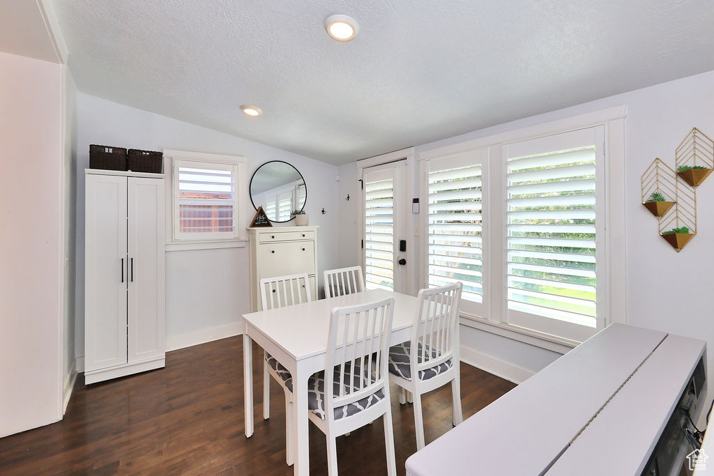 Dining room with a textured ceiling, vaulted ceiling, recessed lighting, baseboards, and dark wood-style floors