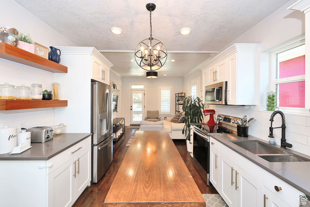 Kitchen featuring a sink, dark countertops, a textured ceiling, dark wood-style floors, and stainless steel appliances