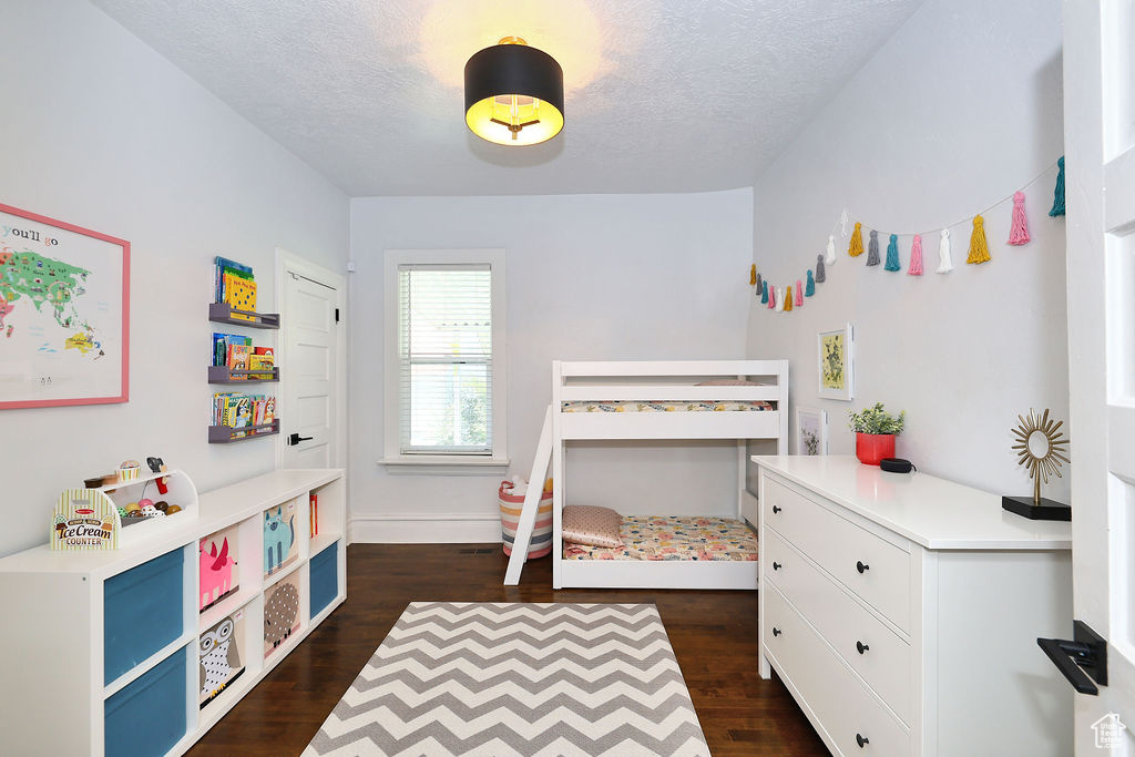 Bedroom with a textured ceiling, baseboards, and dark wood-style floors