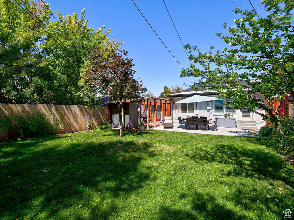View of yard with a patio area, a fenced backyard, and an outbuilding