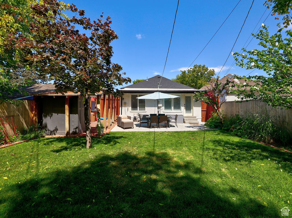 Back of house featuring a fenced backyard, outdoor lounge area, a patio, and a lawn