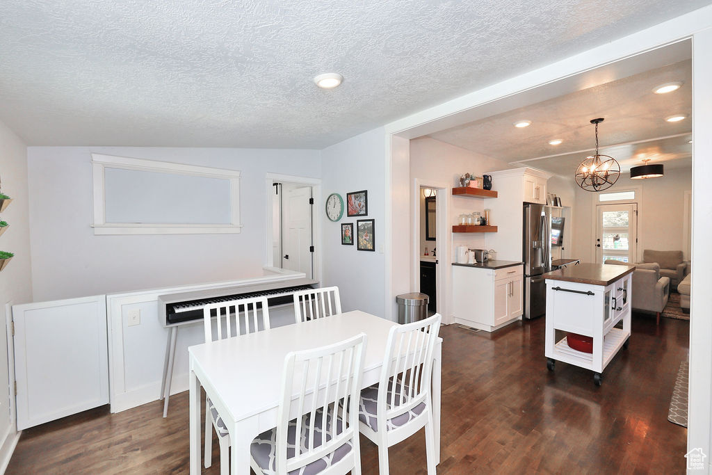 Dining space with a chandelier, a textured ceiling, dark wood-style flooring, and recessed lighting