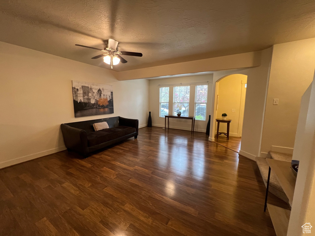 Living area featuring arched walkways, ceiling fan, a textured ceiling, and wood finished floors