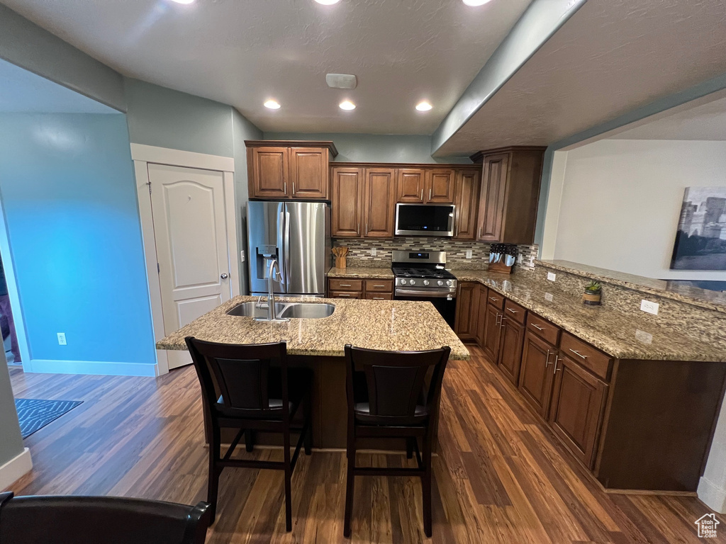 Kitchen with stainless steel appliances, baseboards, dark wood finished floors, and a sink