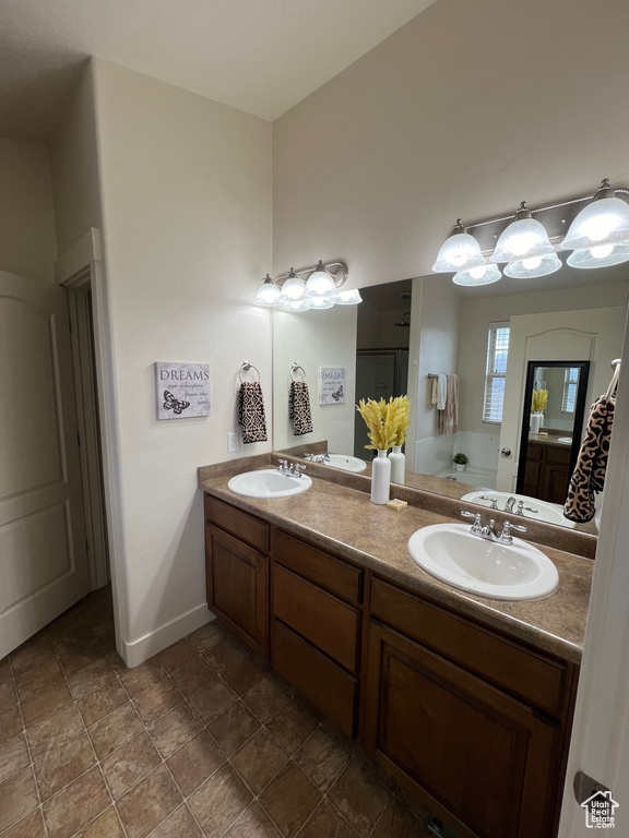 Bathroom with double vanity, a sink, baseboards, and stone finish flooring