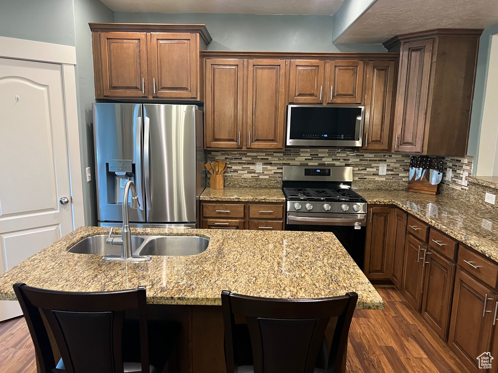 Kitchen featuring stainless steel appliances, dark wood finished floors, decorative backsplash, and a sink