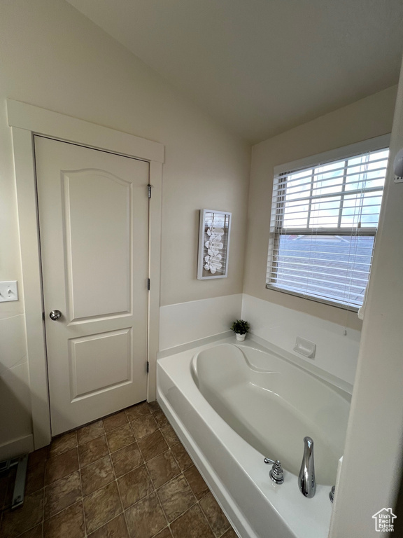 Full bathroom with a bath, lofted ceiling, and stone finish floor