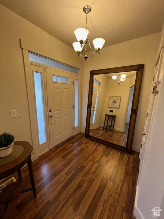 Entryway with an inviting chandelier, baseboards, and dark wood-type flooring