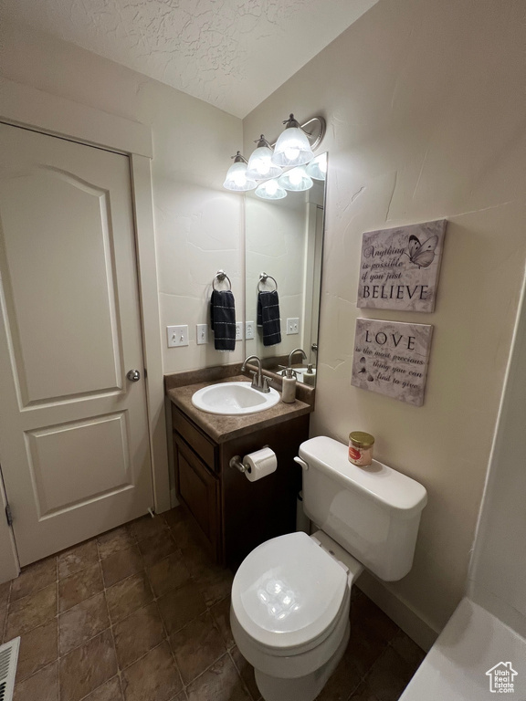 Bathroom with vanity, a textured ceiling, and toilet