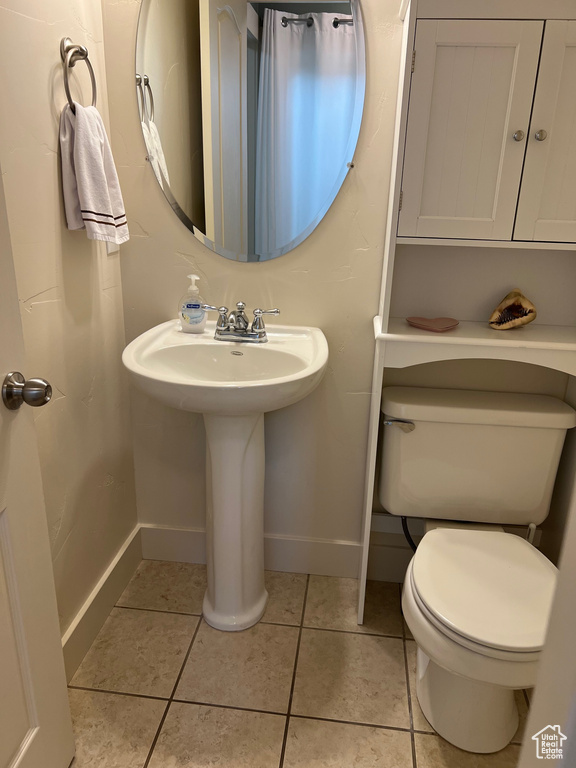 Bathroom with toilet, baseboards, a sink, and tile patterned floors