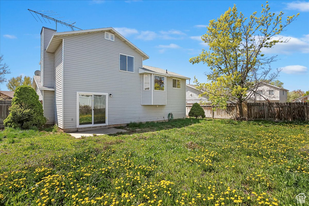 Rear view of house with a chimney, fence, and a yard