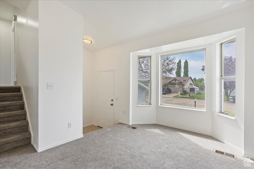 Empty room featuring carpet, visible vents, stairway, and baseboards