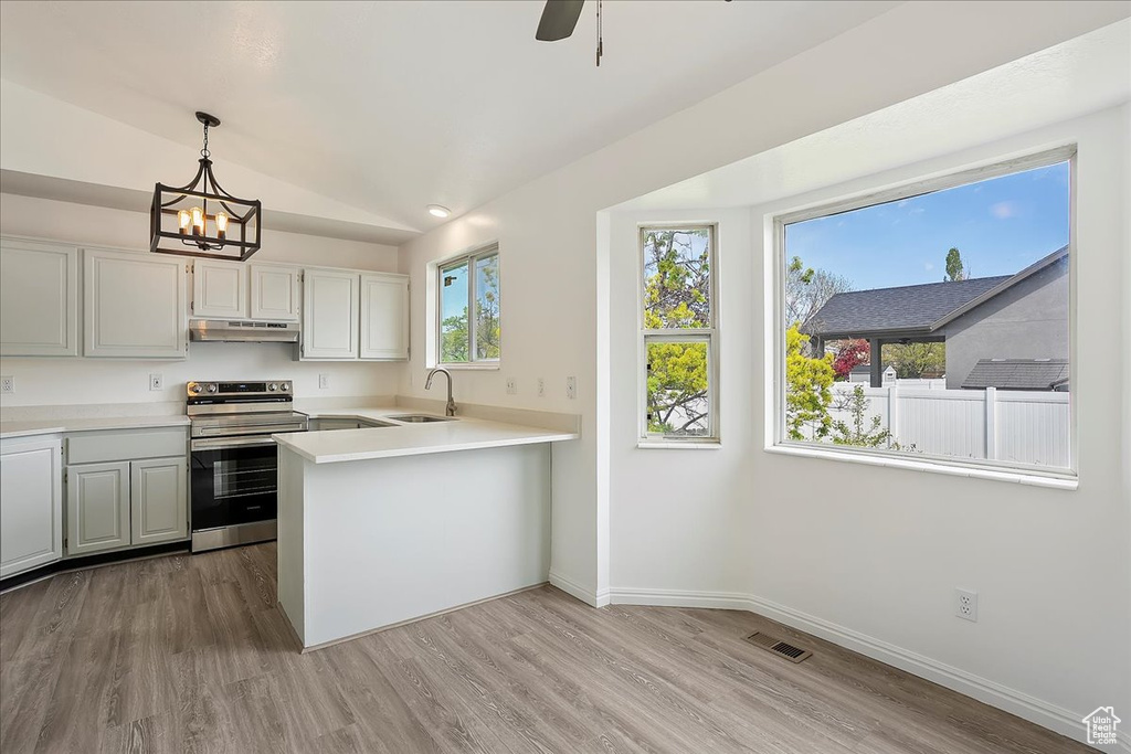 Kitchen featuring a sink, visible vents, stainless steel range with electric stovetop, baseboards, and under cabinet range hood