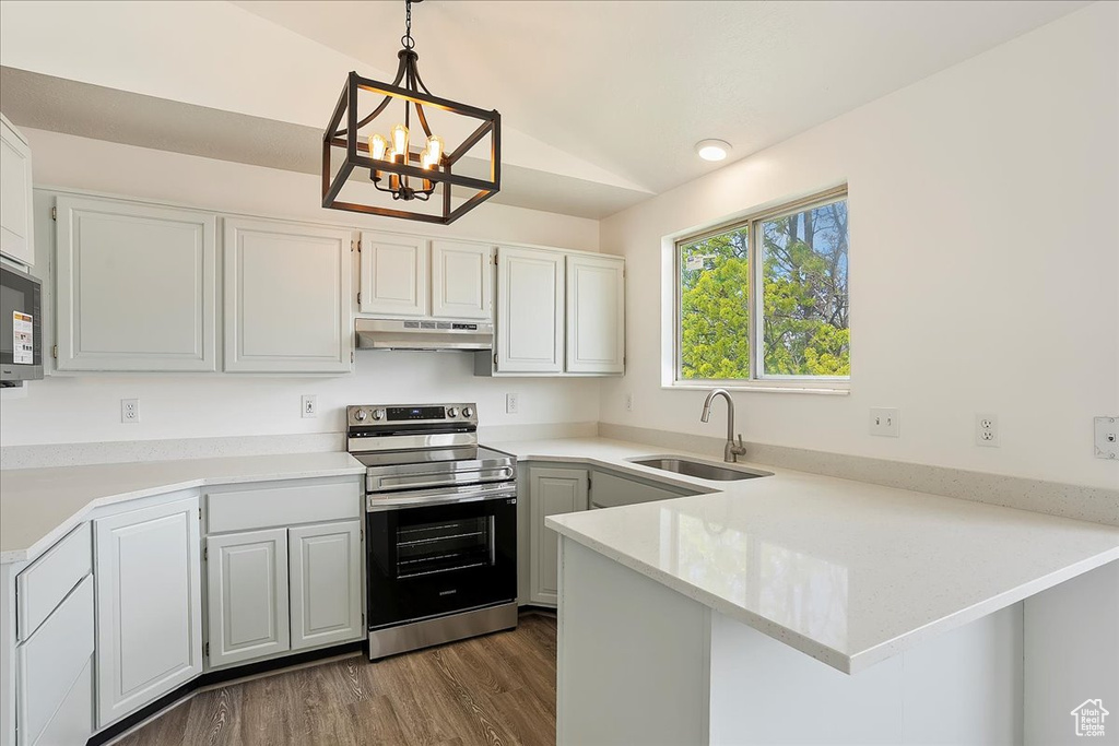 Kitchen with a sink, under cabinet range hood, a peninsula, light countertops, and electric range